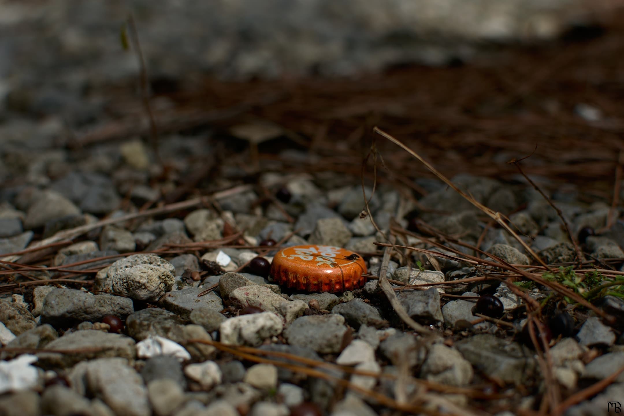 Orange bottle cap on gravel