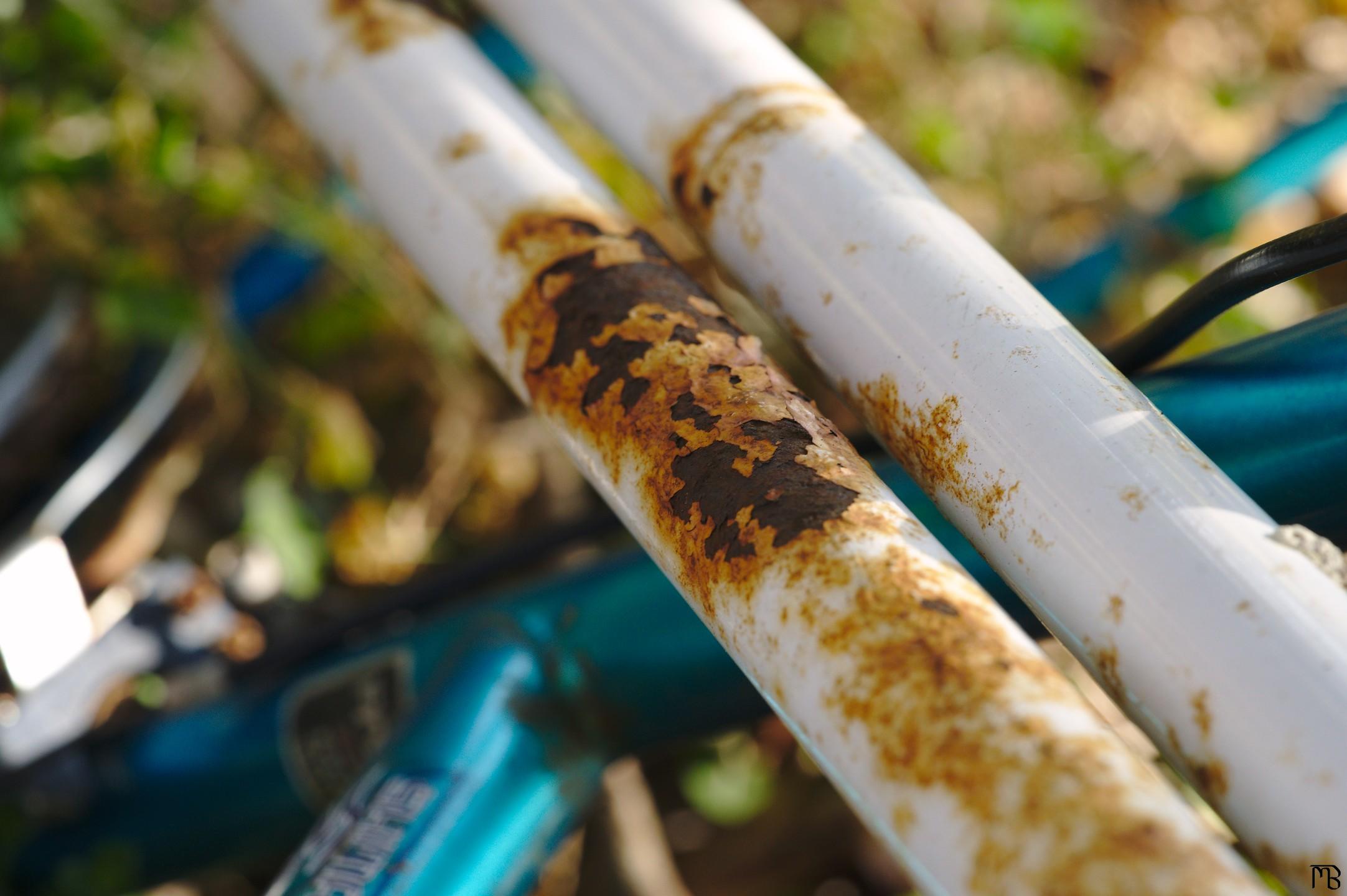 Rusty white pipes above bike