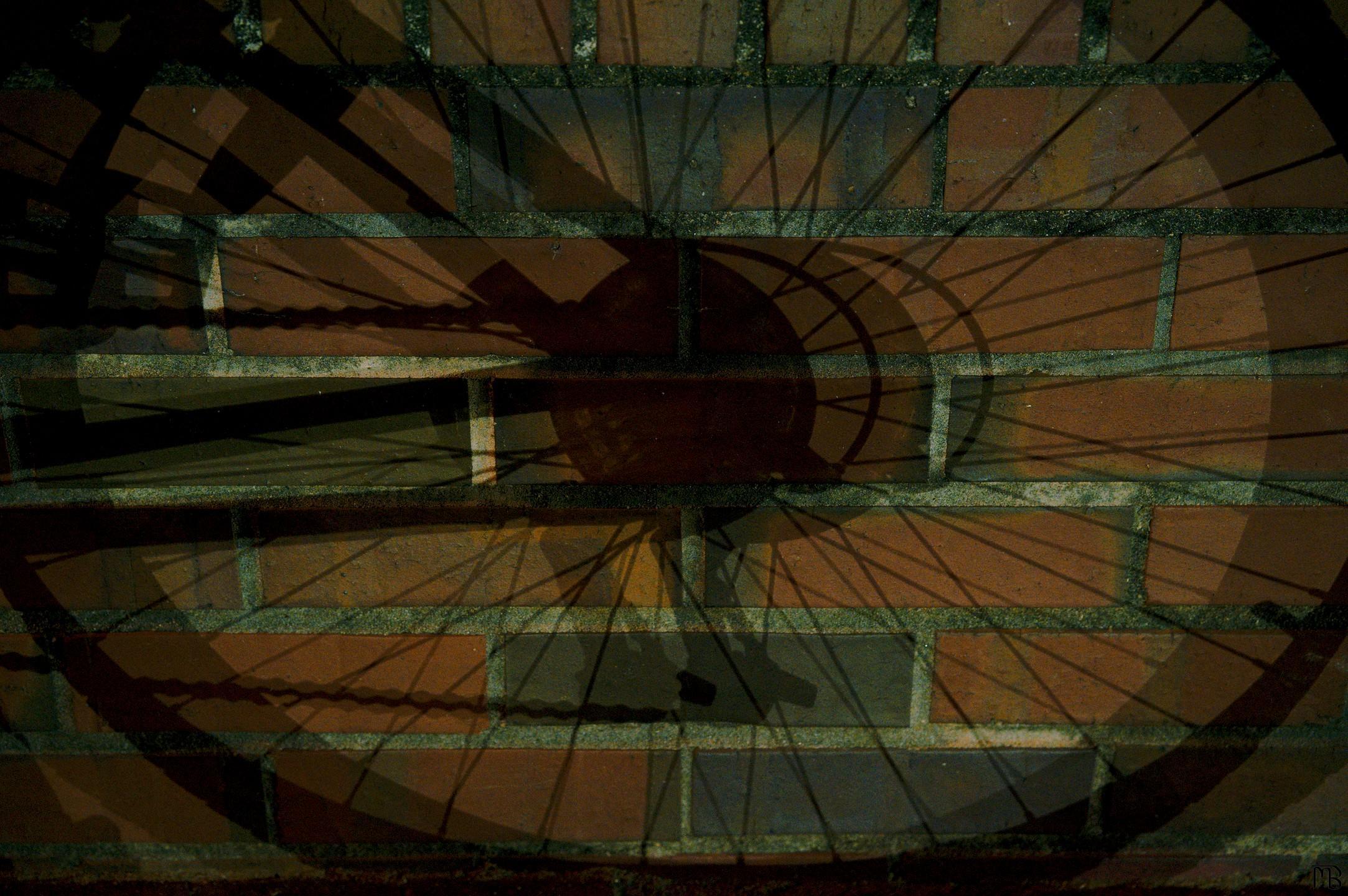 Shadow of bike wheel on brick