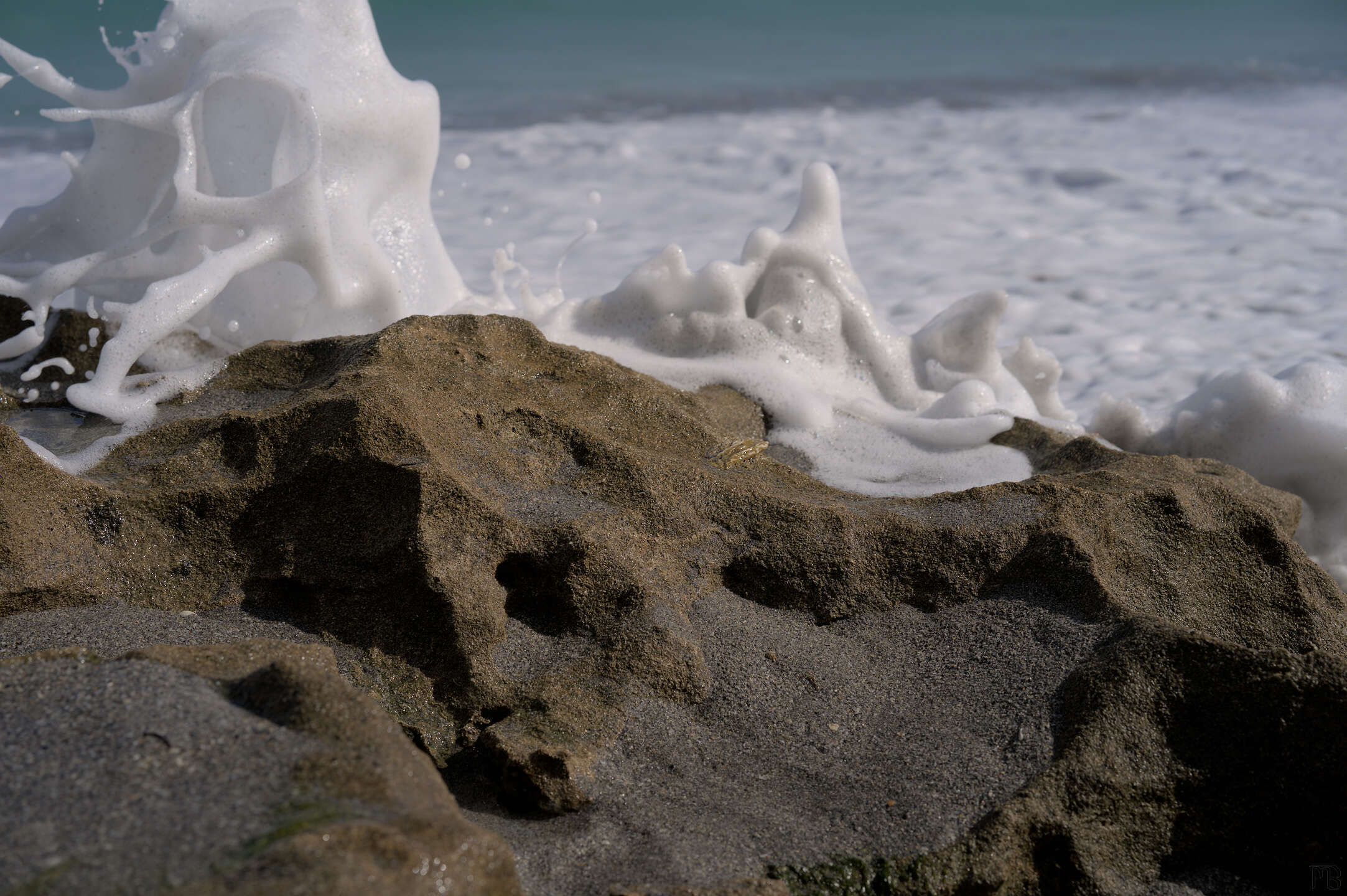 Foamy sea waves on brown rock