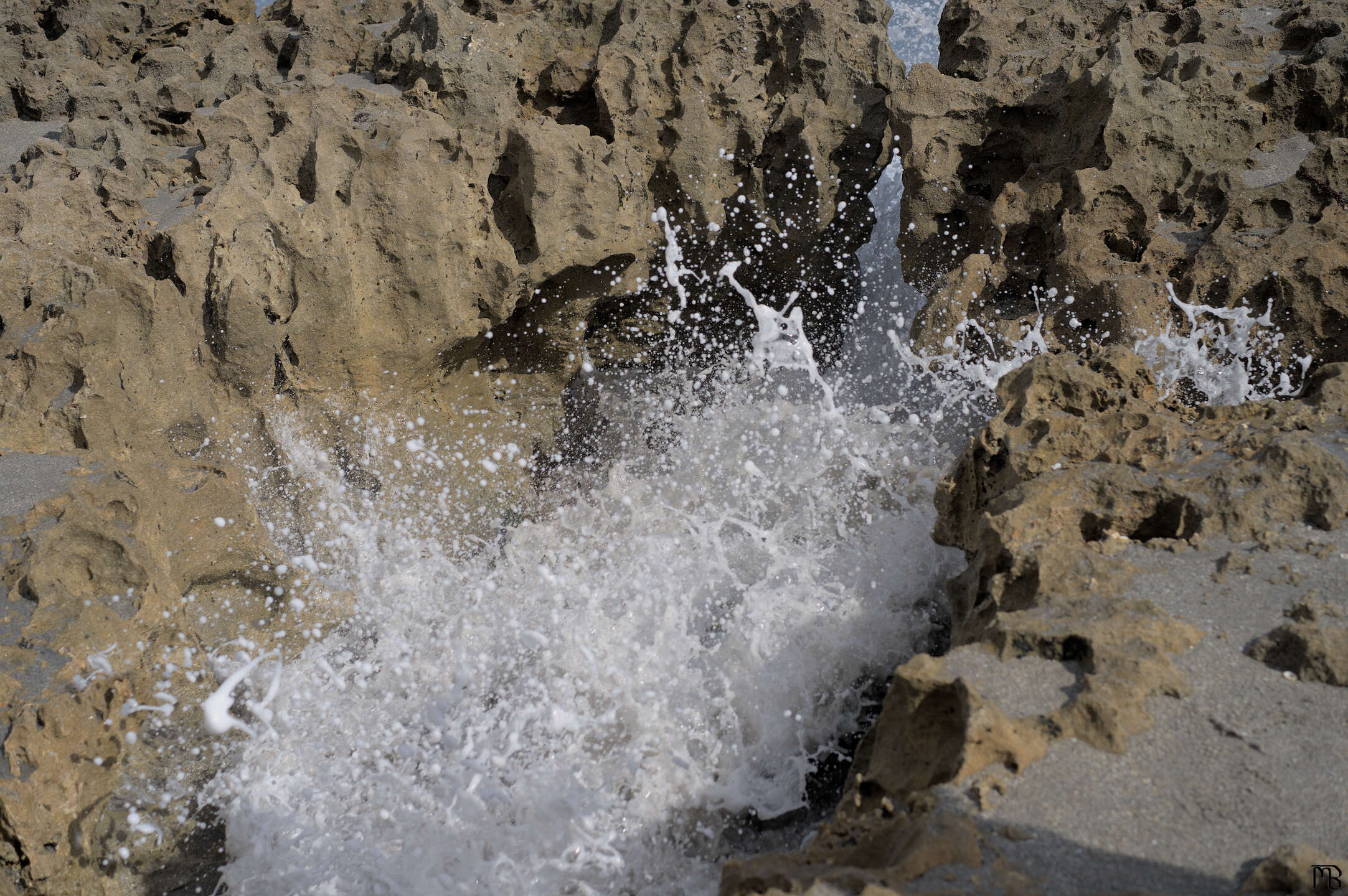 Wave crashes against sea rocks