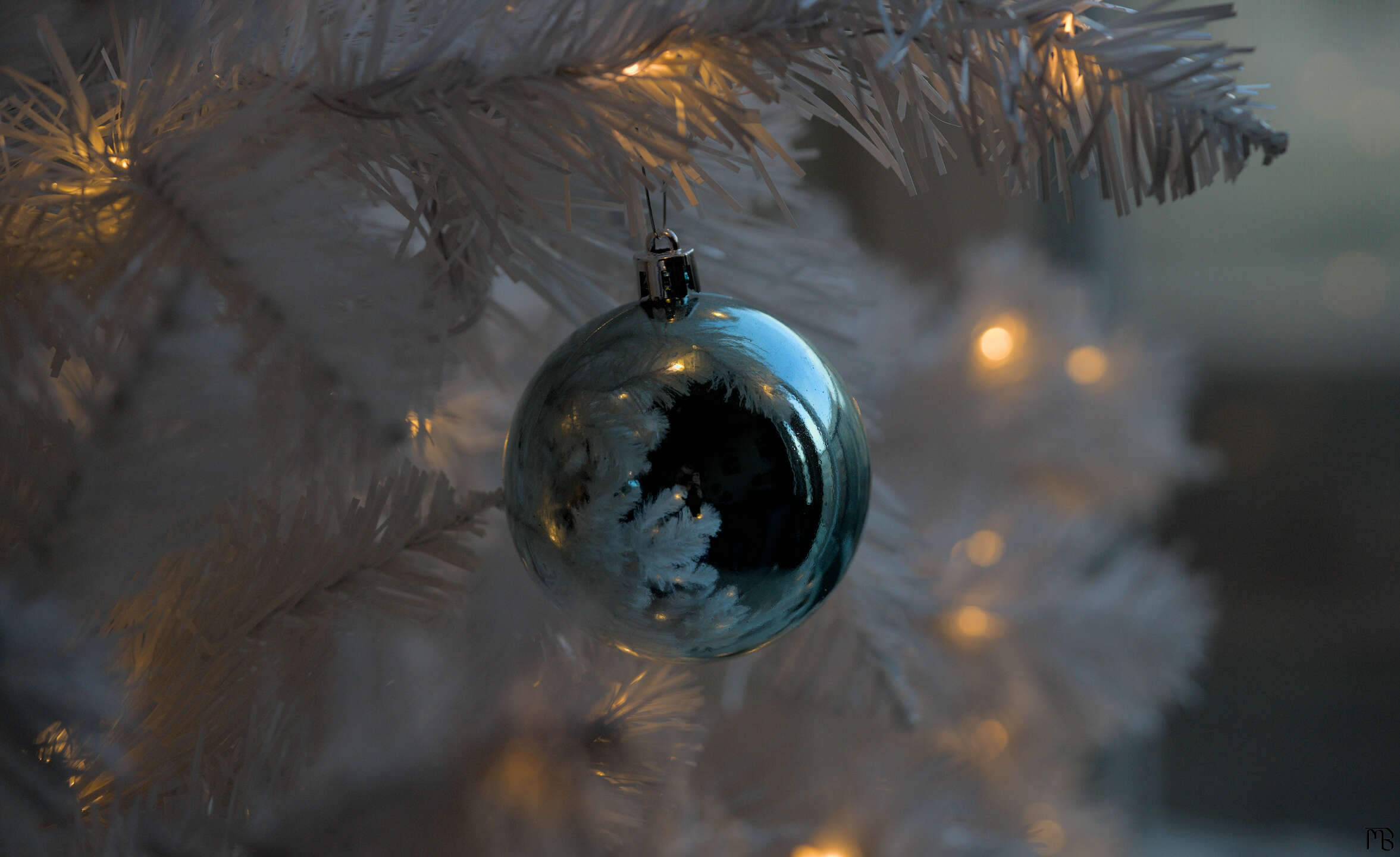Blue ornament on white tree with lights