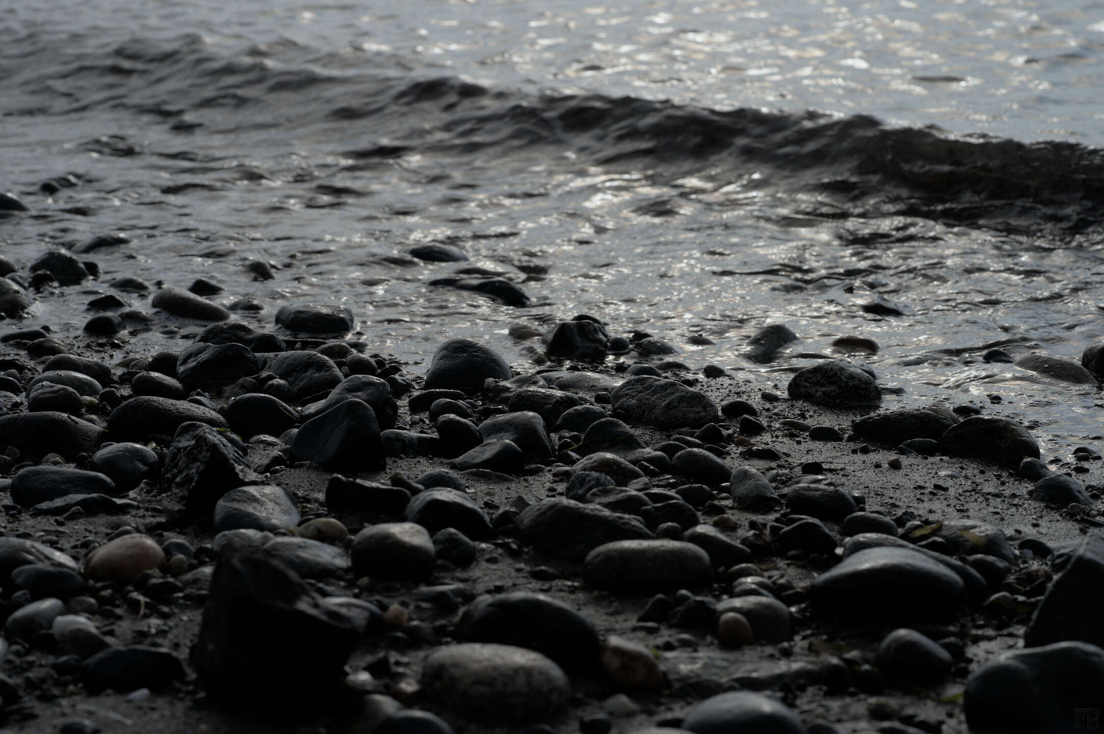 Gray small wave at stony beach