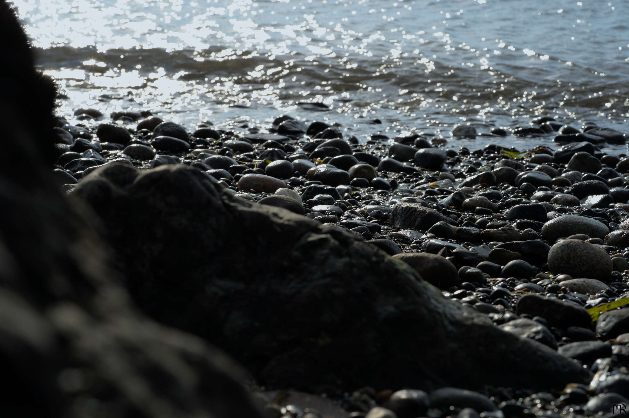 Large rock behind small colorful stony beach