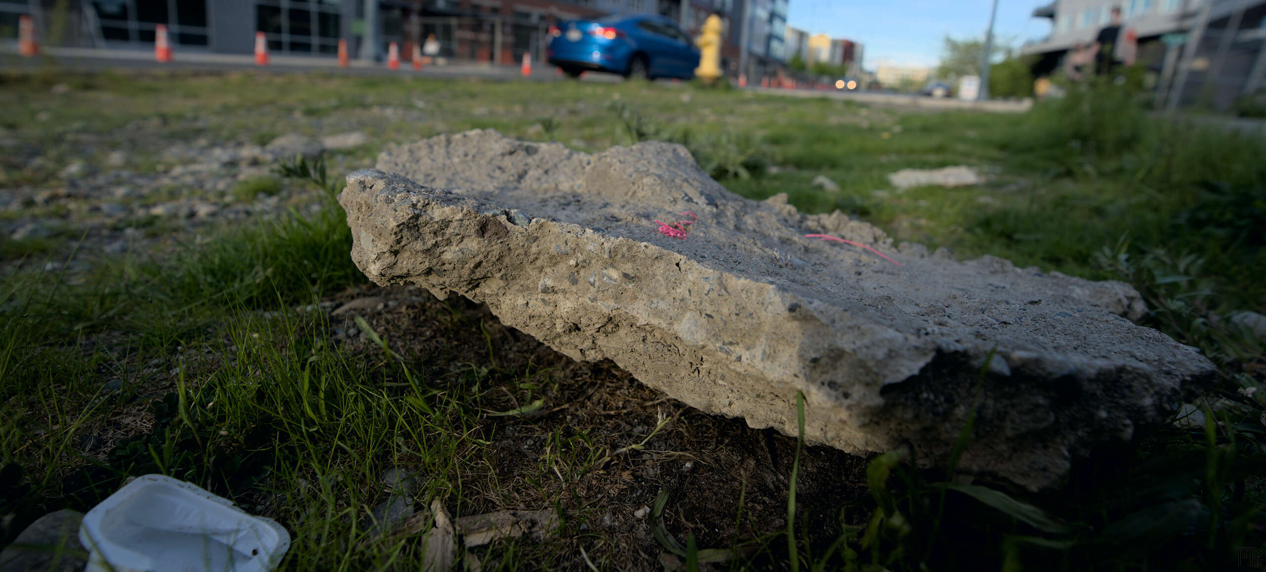 Large piece of concrete in grass by road