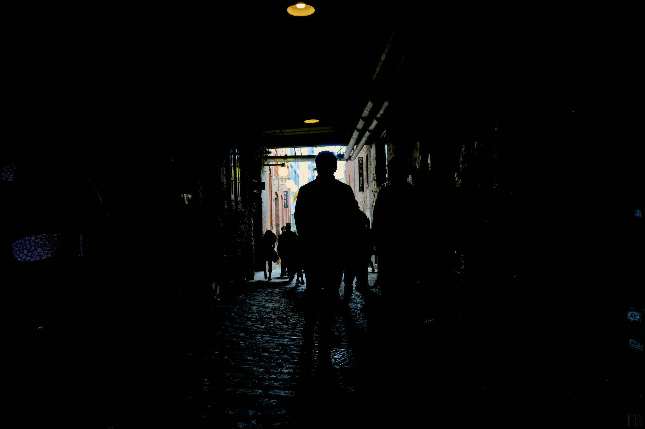 Person silhouetted in dark alley