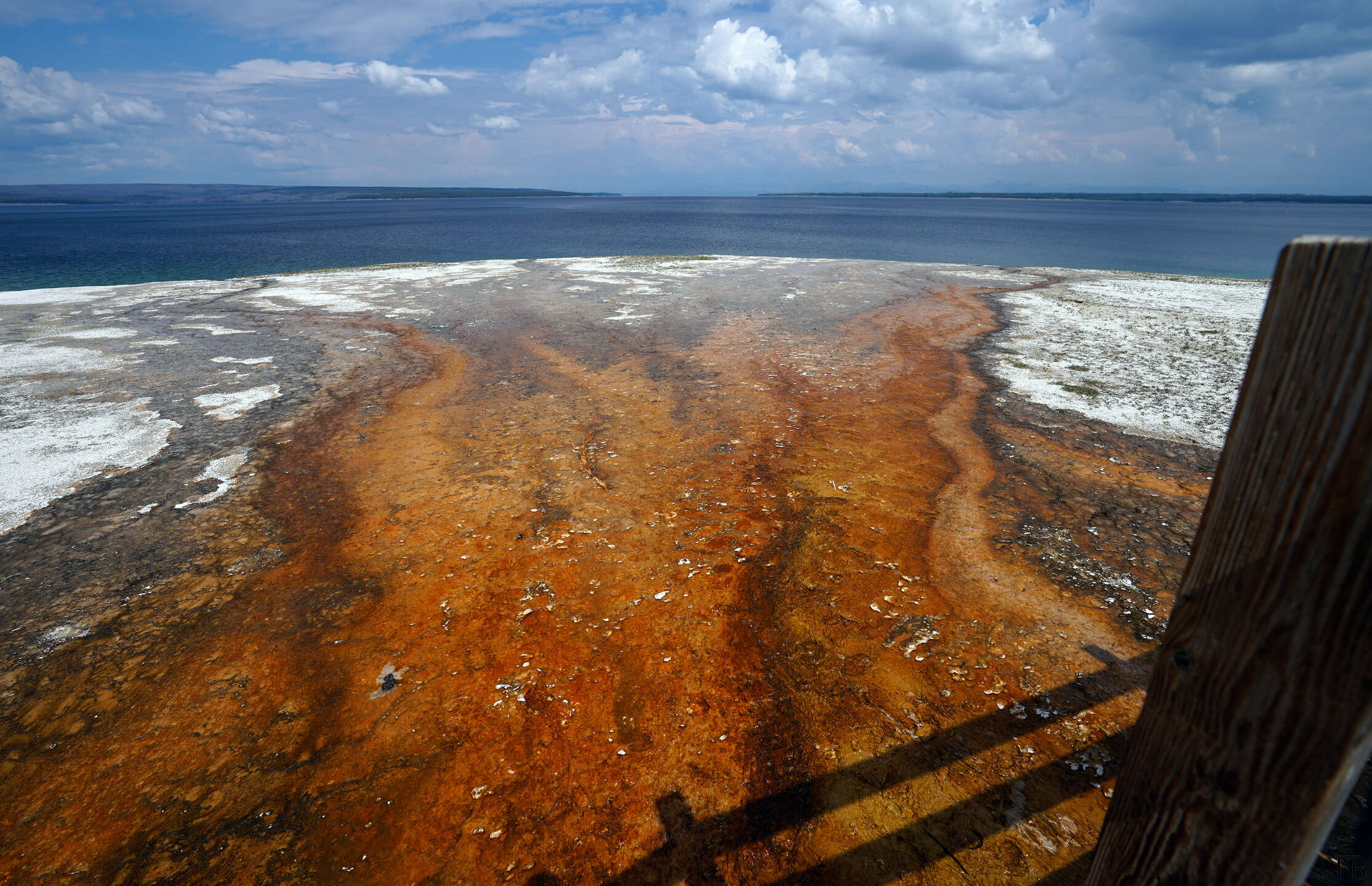 Vibrant orange hot spring flowing into lake at Yellowstone