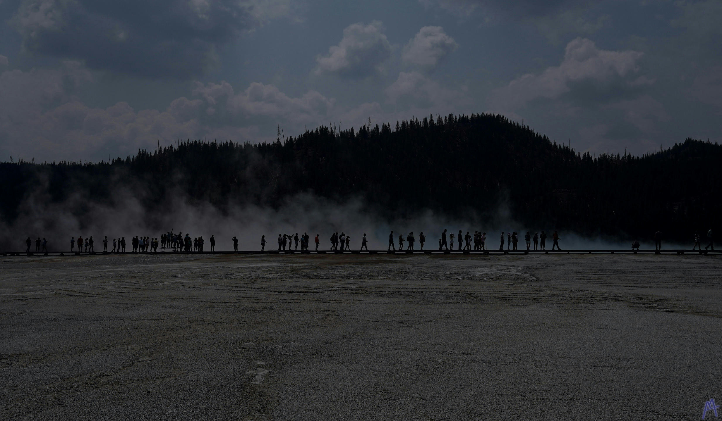 Black and gray line of people in front of steam at Yellowstone