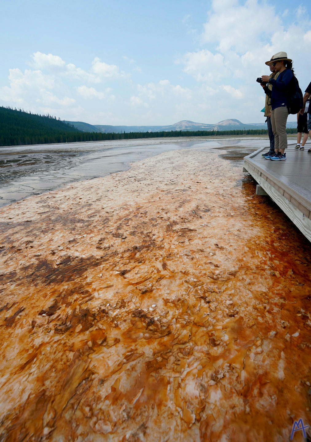 Deep orange hot spring runoff with mountains in the background at Yellowstone