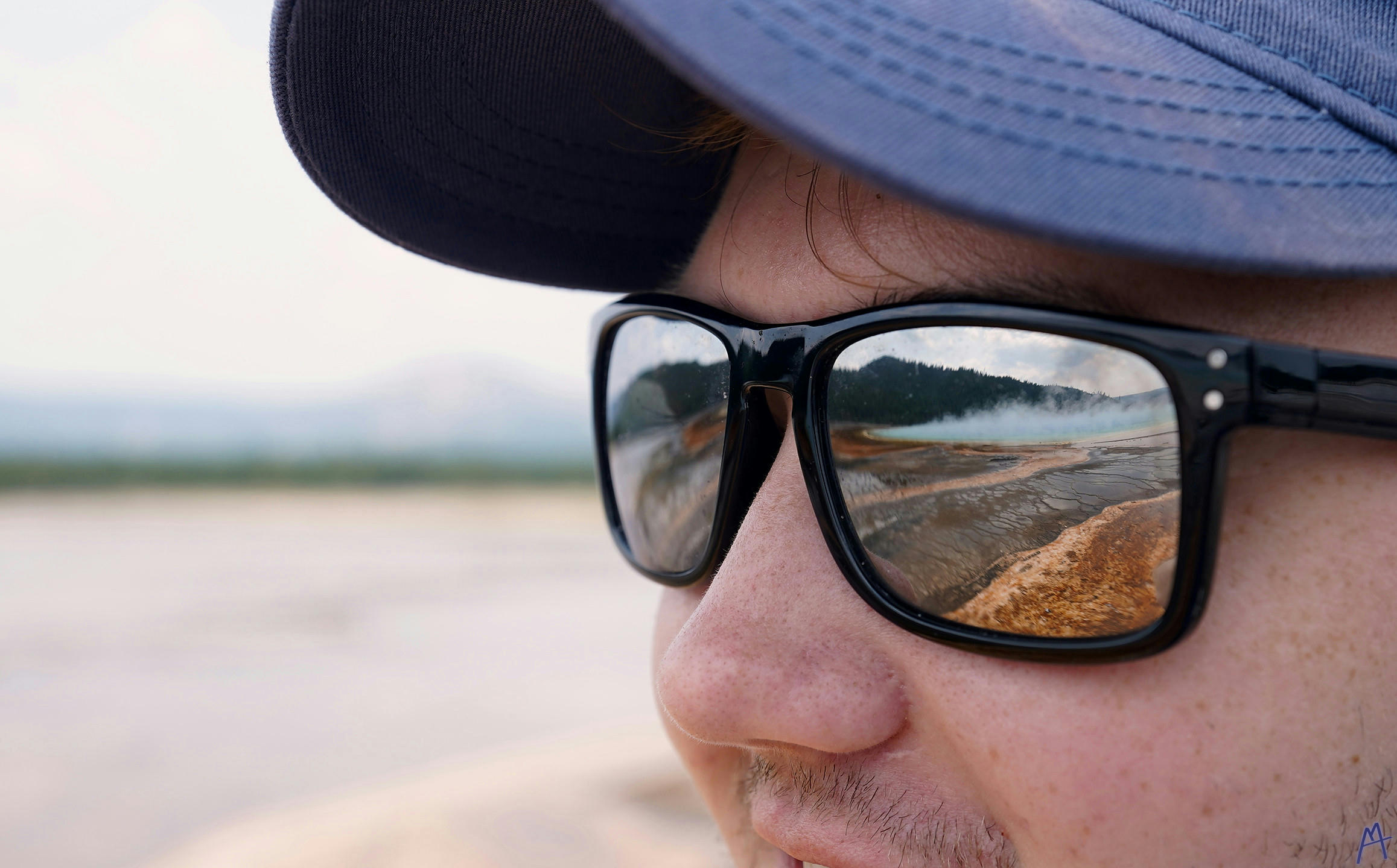 My brother with sunglasses reflecting a hot spring at Yellowstone