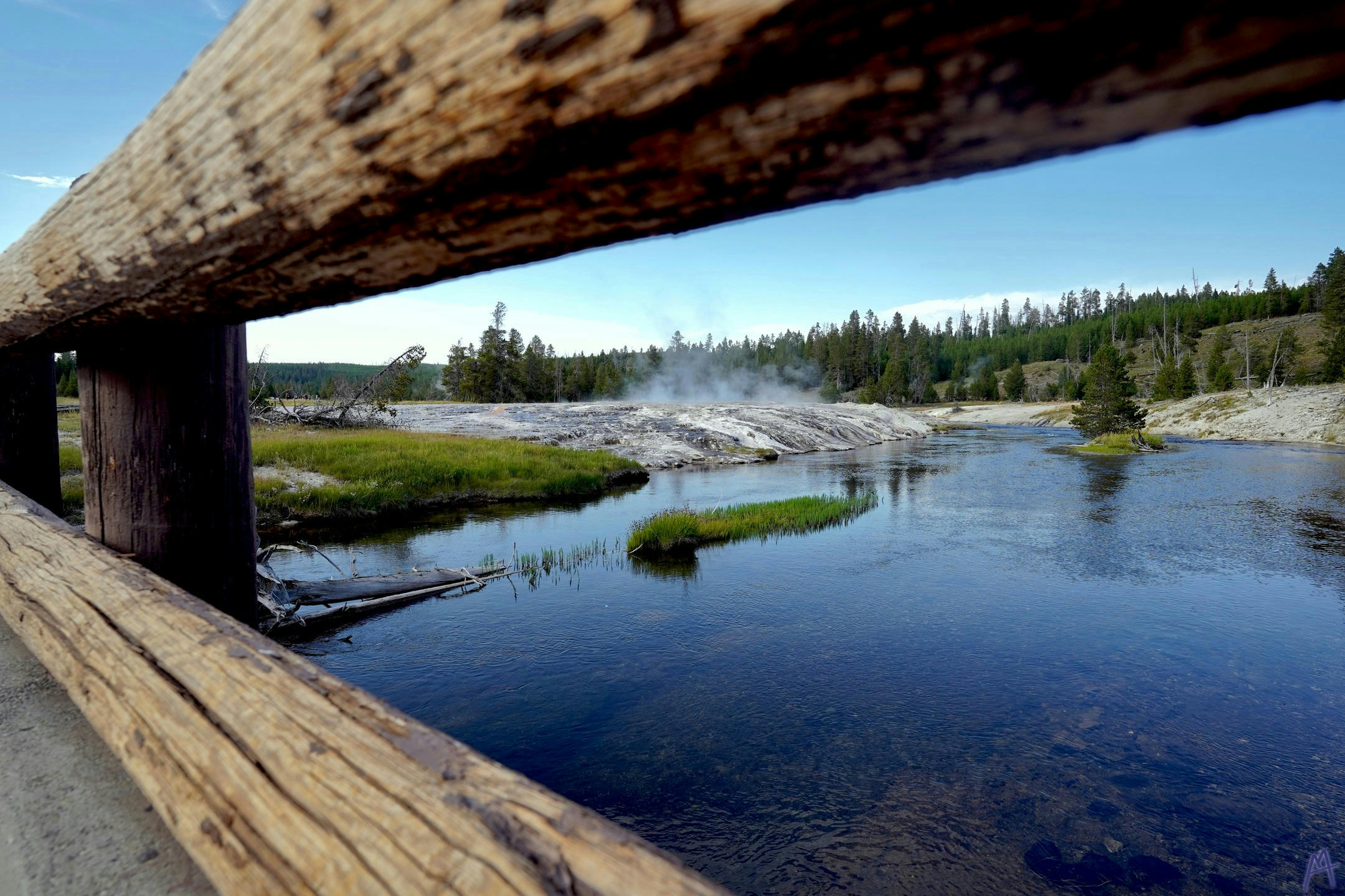 Deep blue water through log fence at Yellowstone