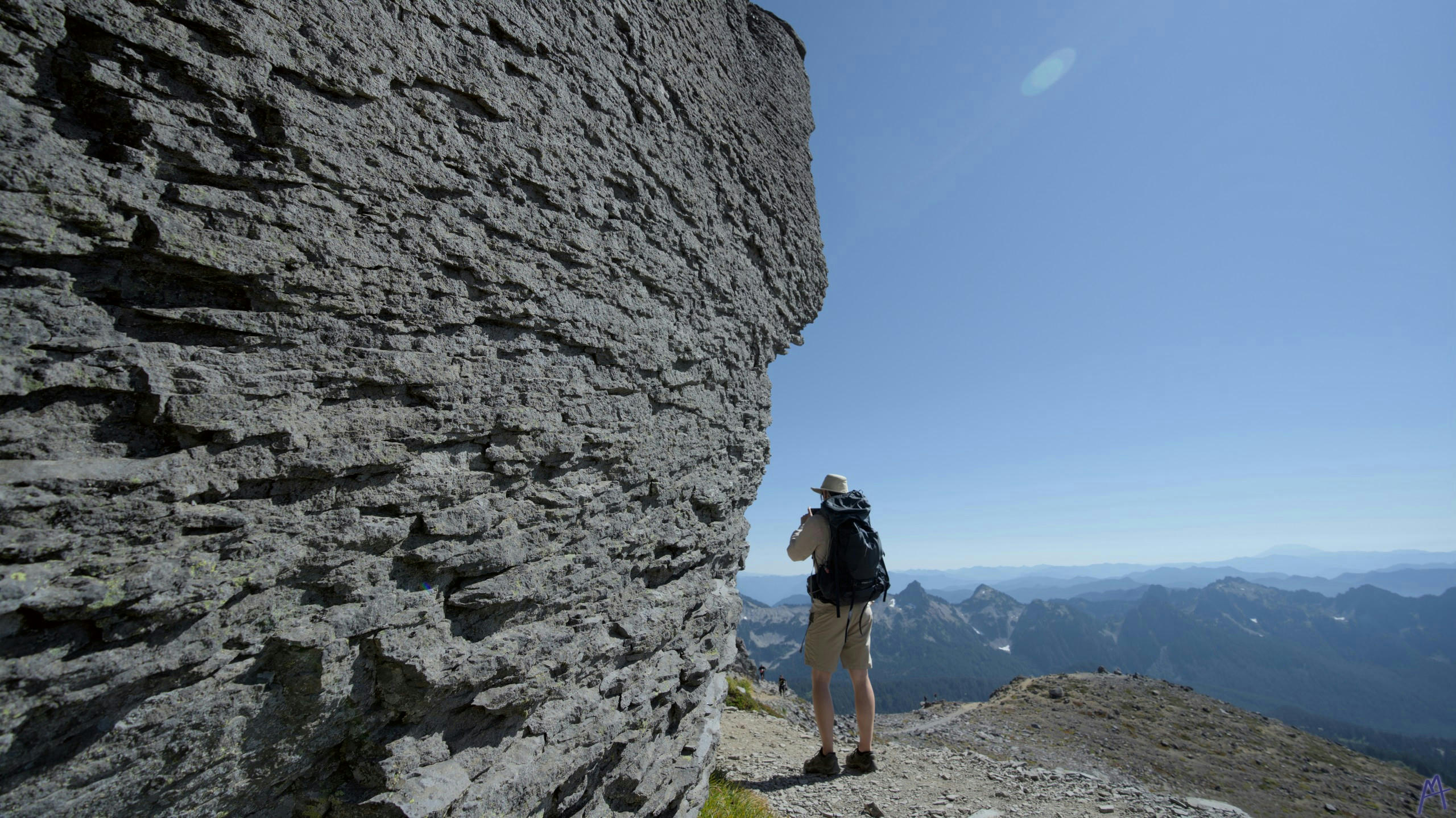 Raw stone near a path framing a hiker at Rainier