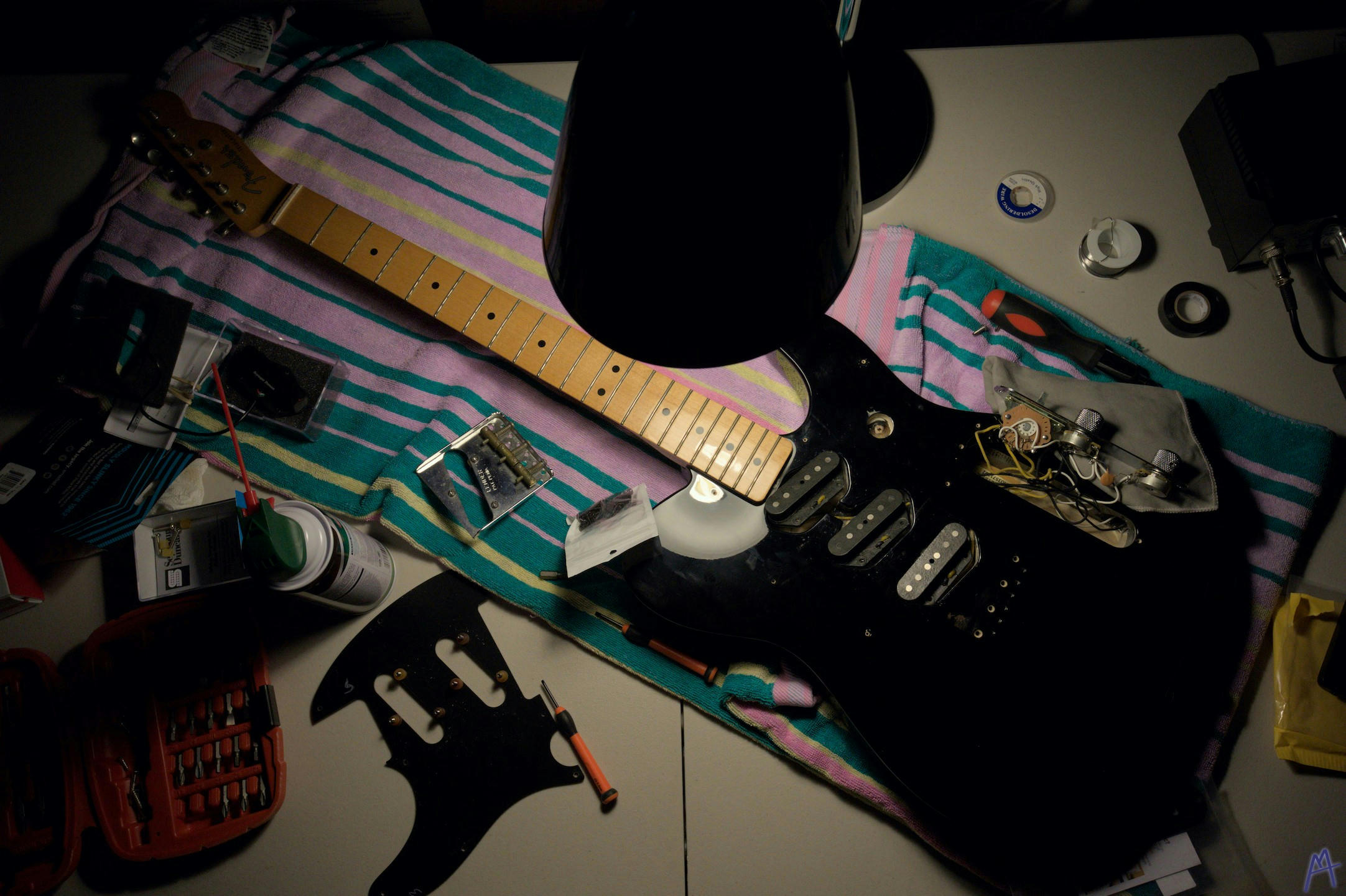 Black guitar on a workbench surrounded by tools