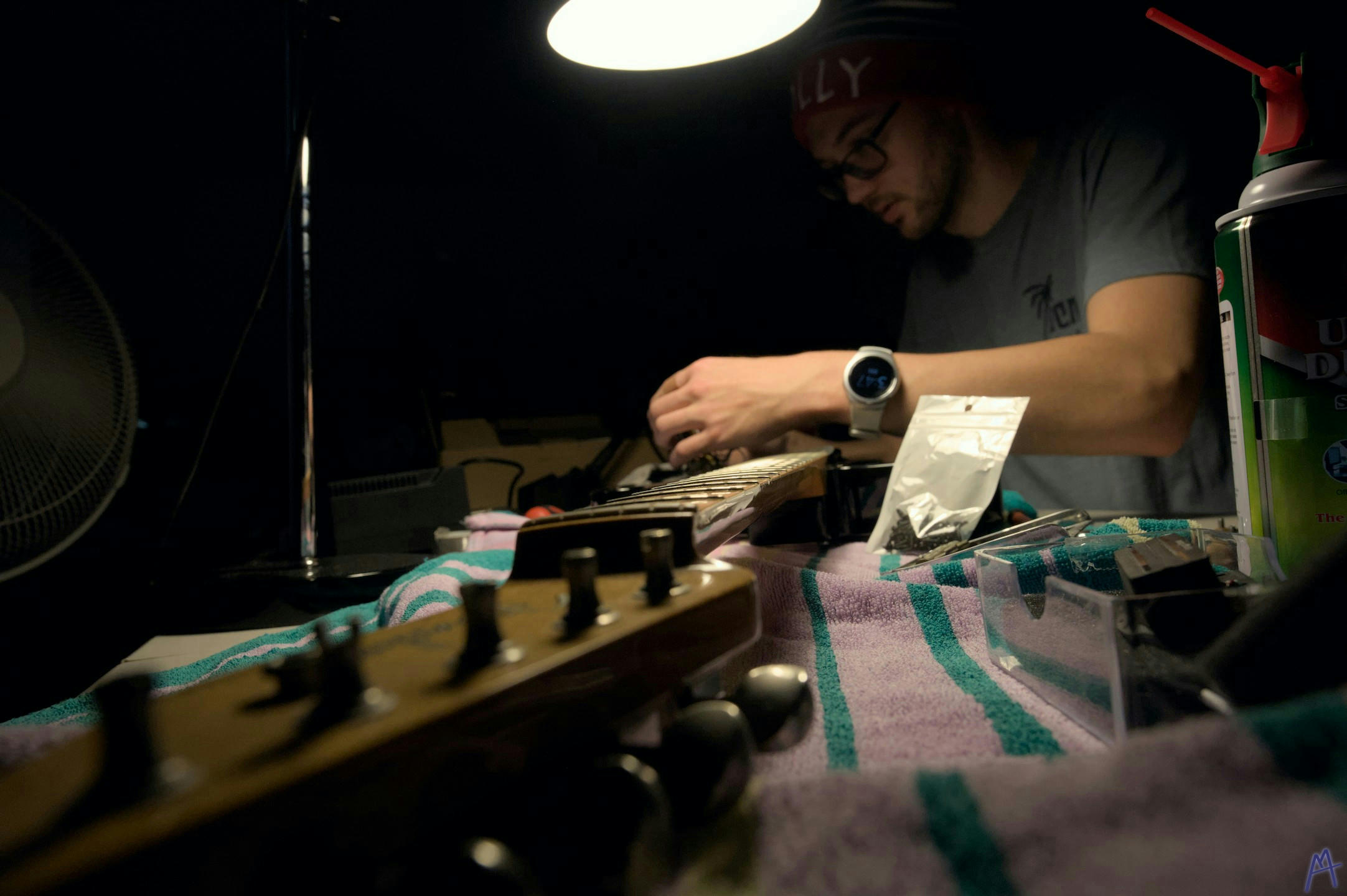 My brother working on his black guitar on a workbench