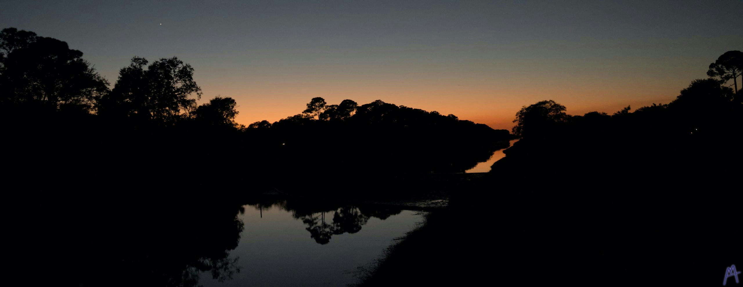 Orange and blue sunset from the side of a canal