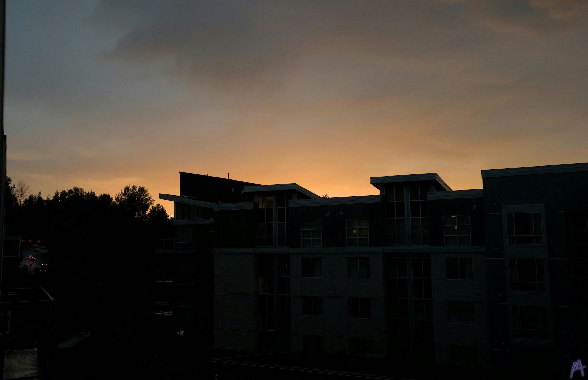 Orange cloudy sunset behind a building