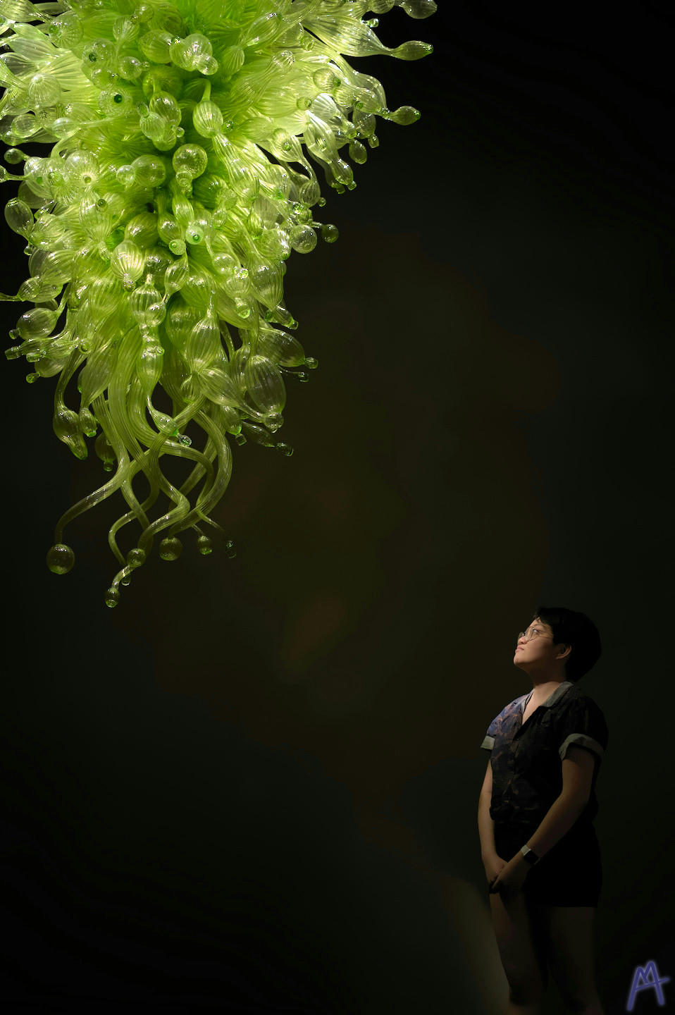 A green glass sculpture hanging above a woman