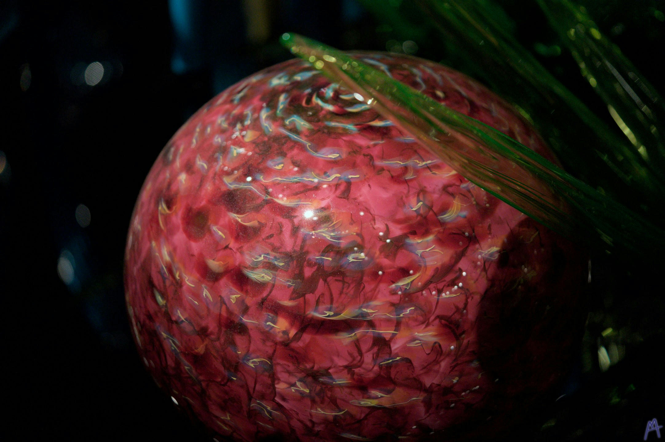 Red patterned glass ball near green glass
