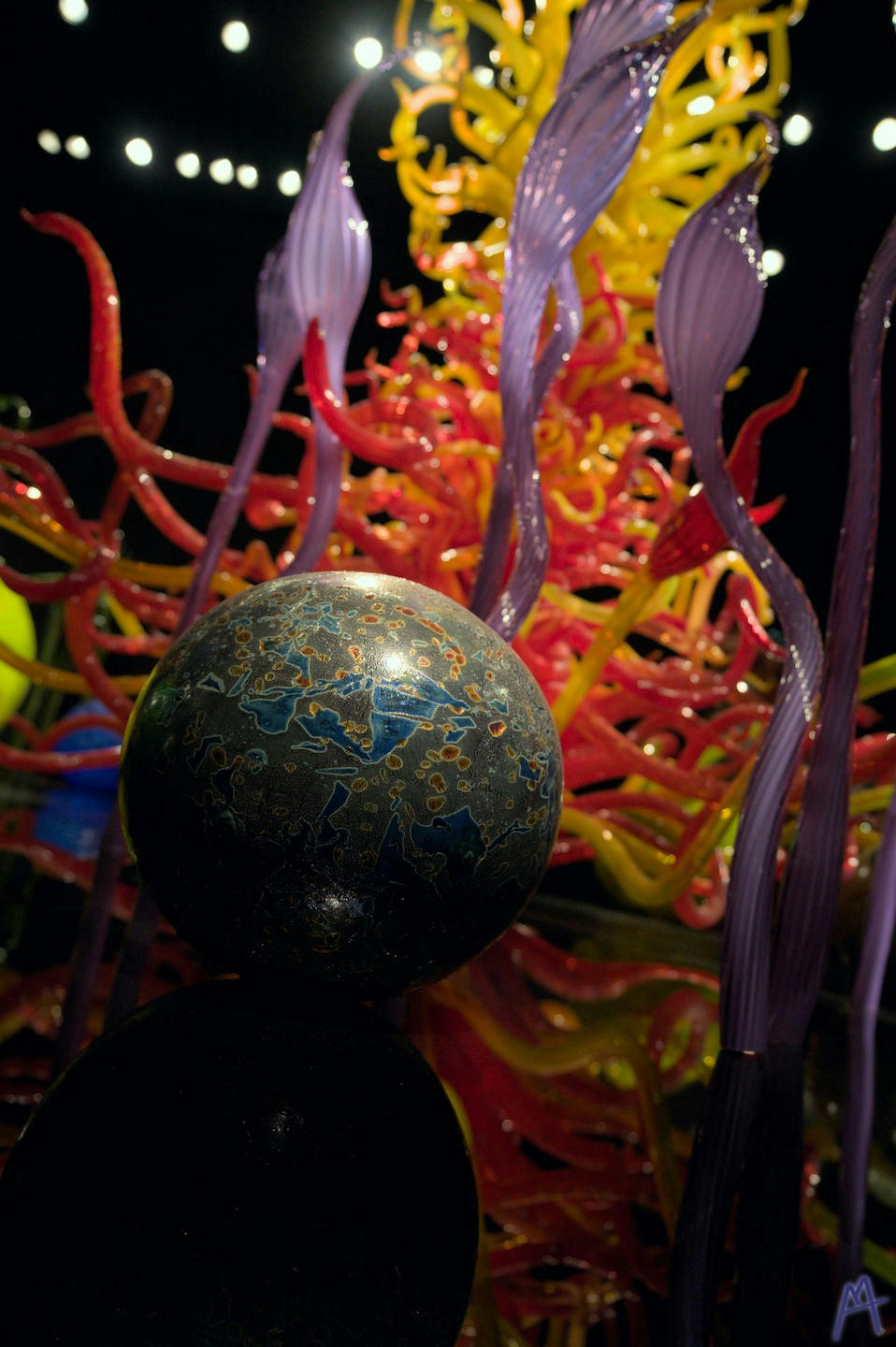 Blue and stone glass ball in front of red and yellow tower