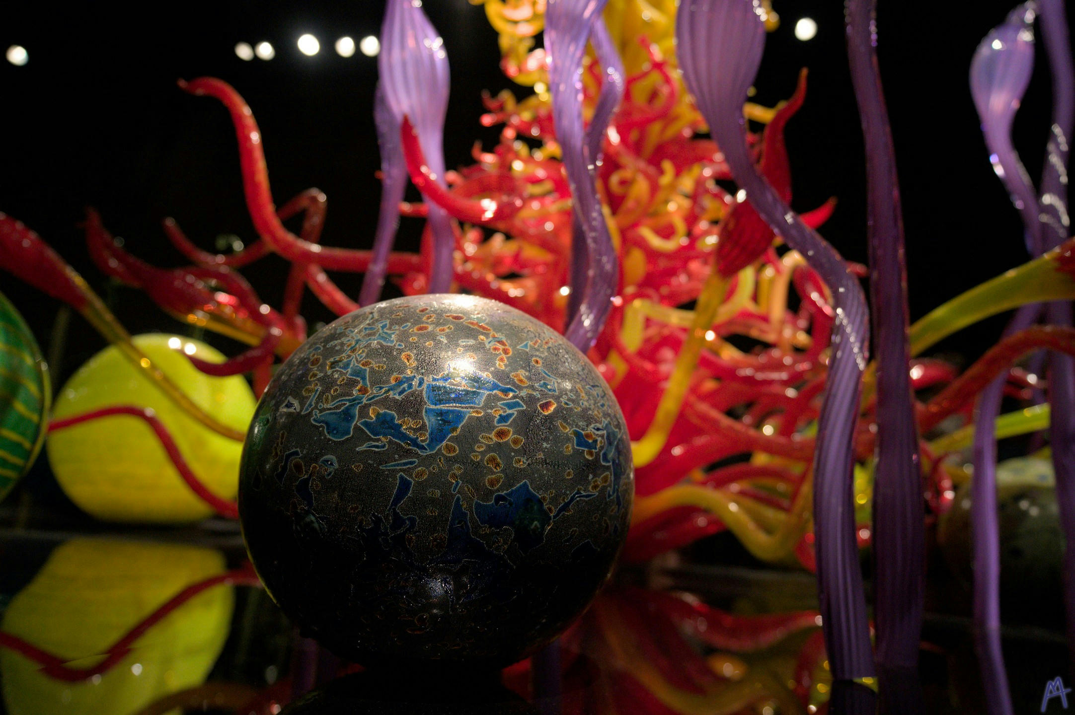Stone and blue glass ball in front of red and yellow tower