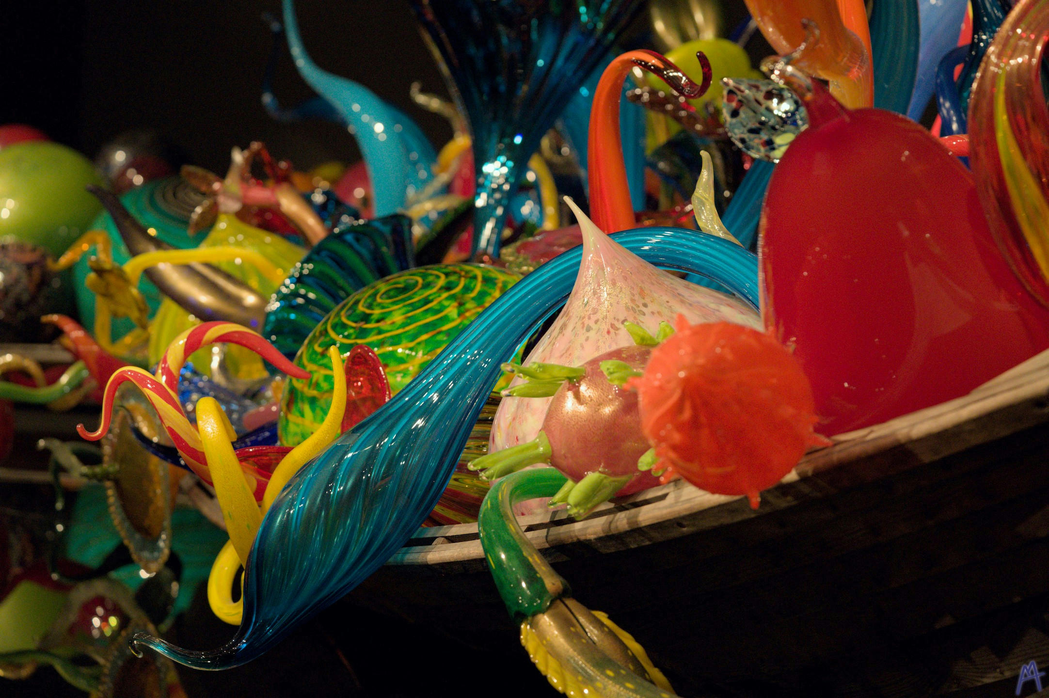 Blue green and red glass sculptures spilling out of a boat
